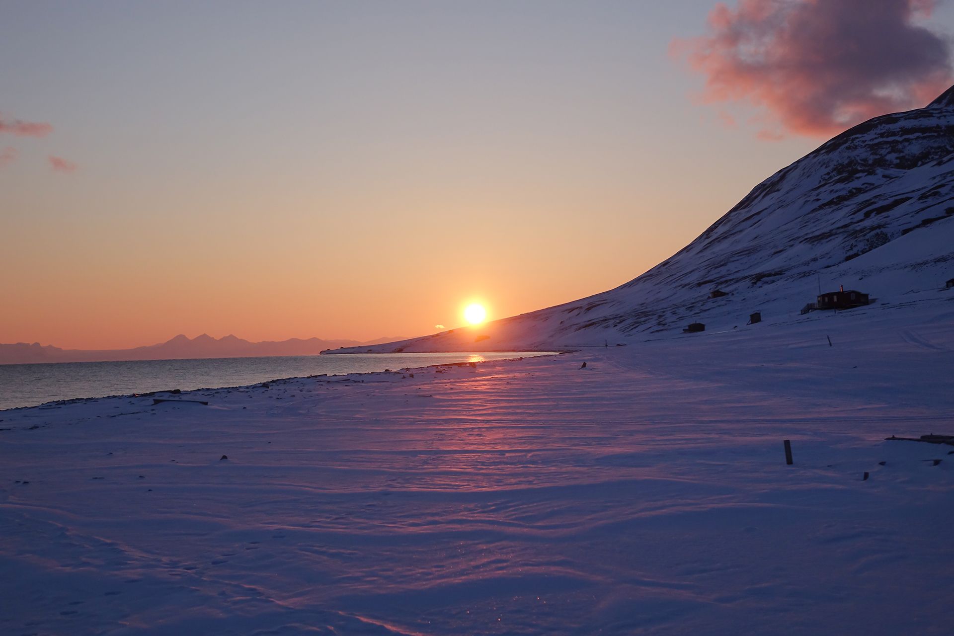 Midnattssola som ligger lavt over en fjellrygg