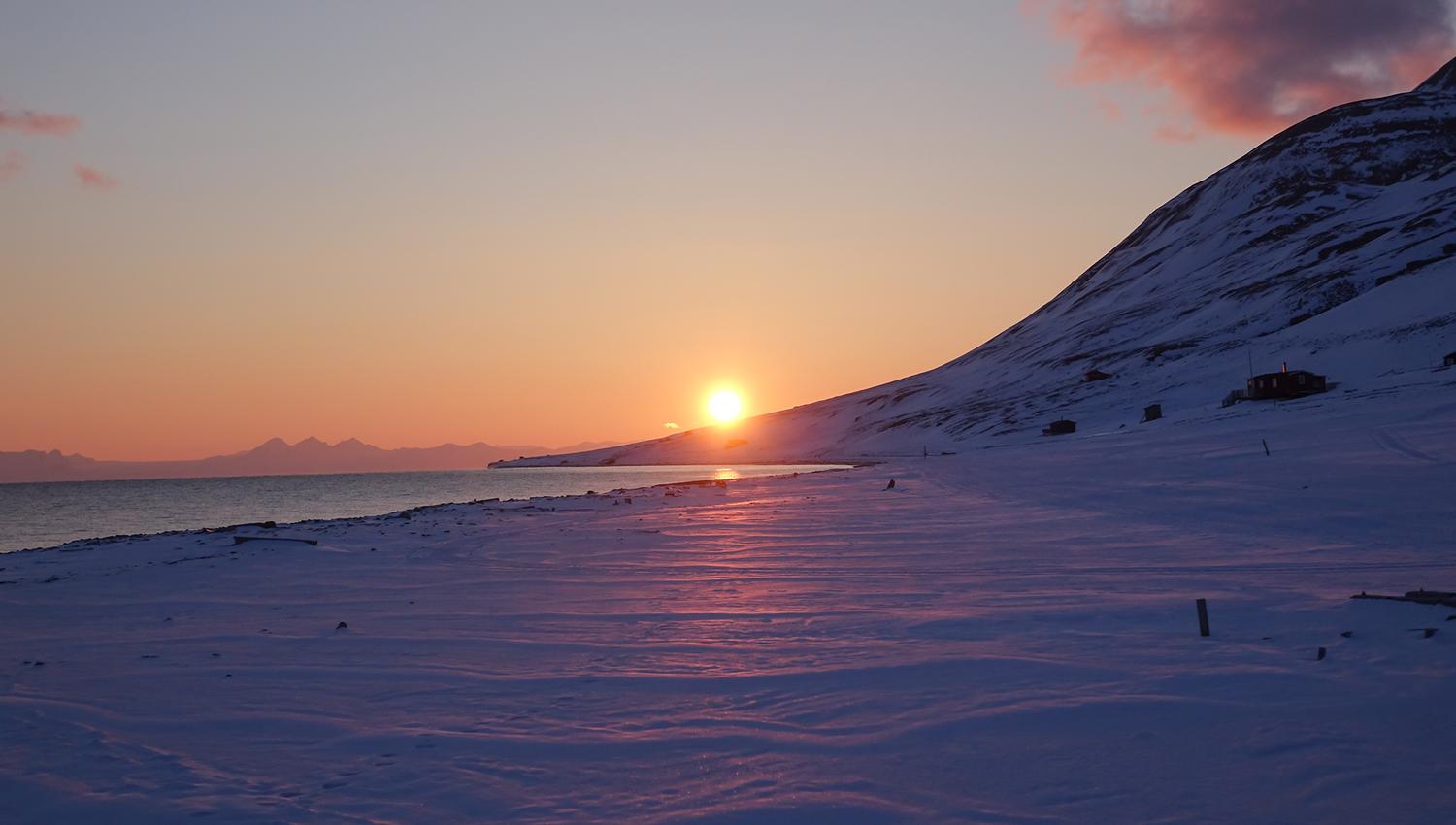 Midnattssola som ligger lavt over en fjellrygg