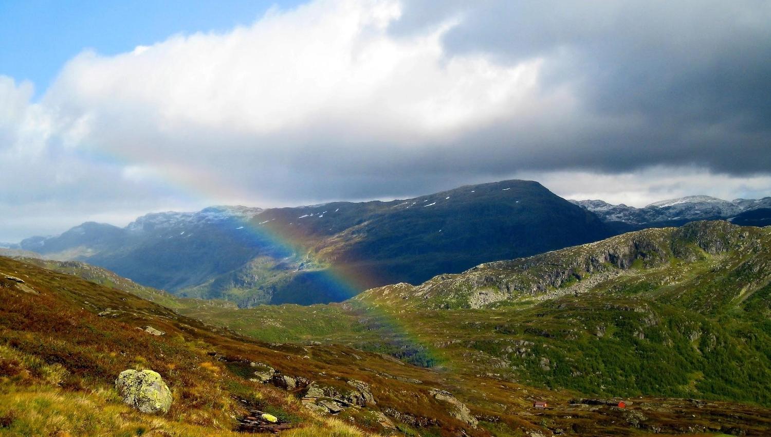 A view over several mountains with a rainbow in the middle of the picture