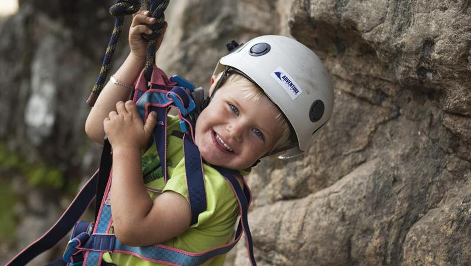 Young smiling boy climbing and rapelling