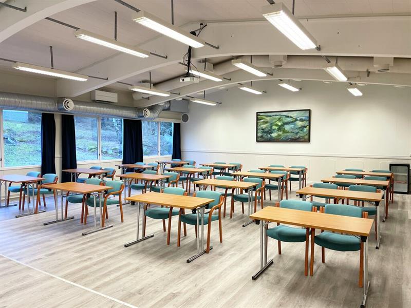 Lyst møterom på Hankø Hotell & Spa, med bord og stoler i klasseromsoppsett og store vinduer.