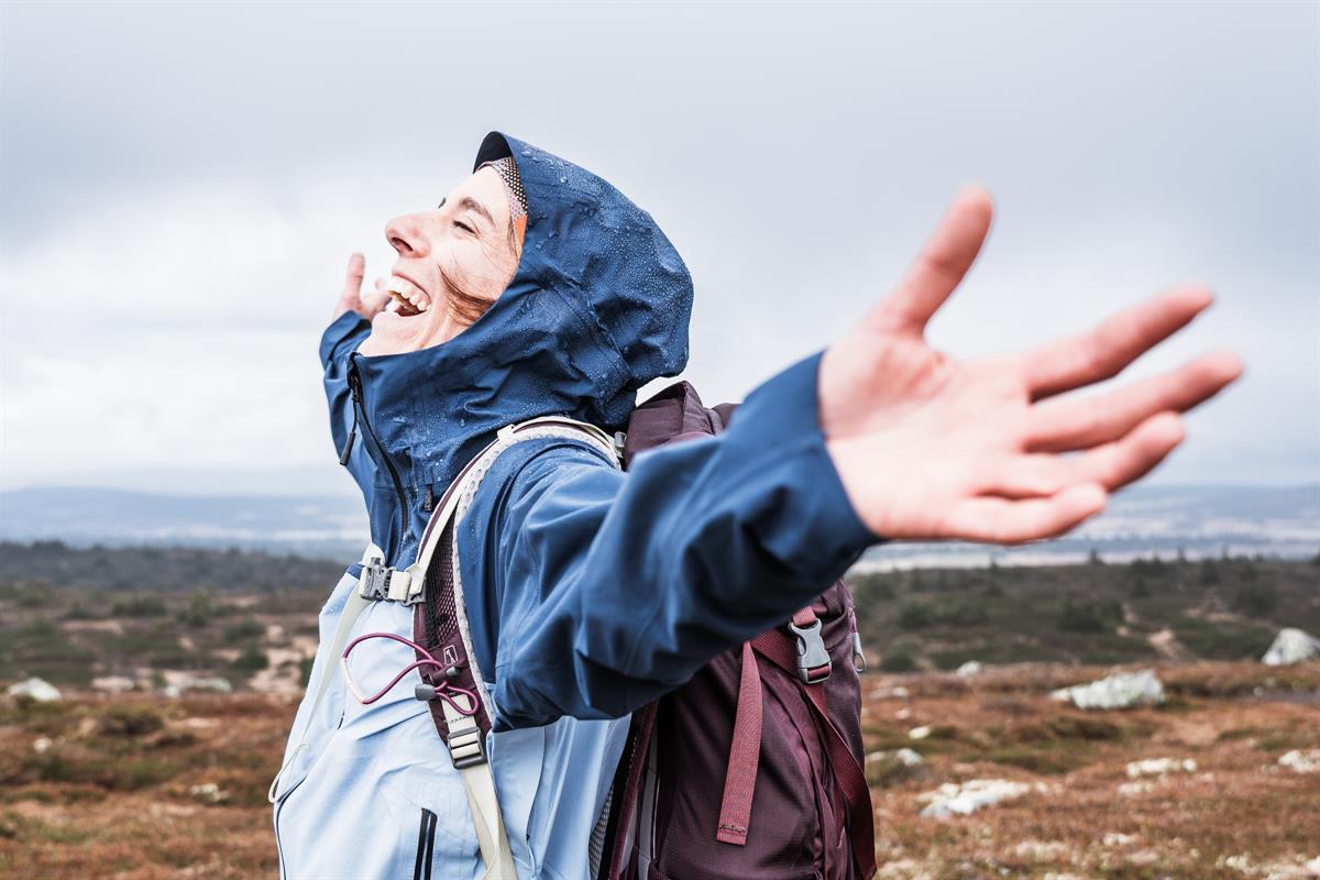 Person with arms outstretched towards open sky in the mountains