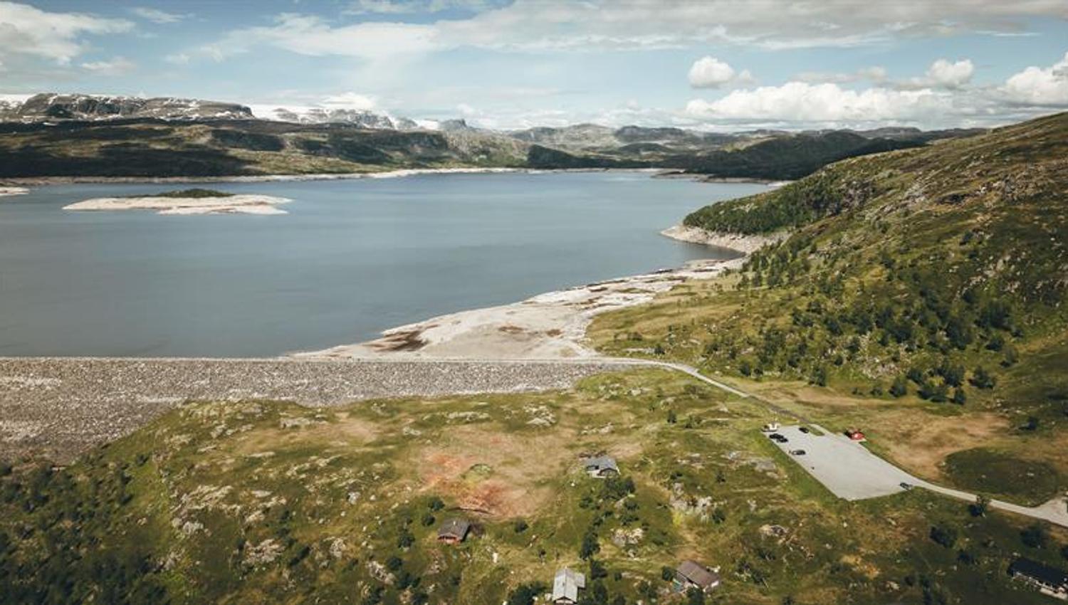 A drone photo showing the parking lot in the front and the dam in the background.