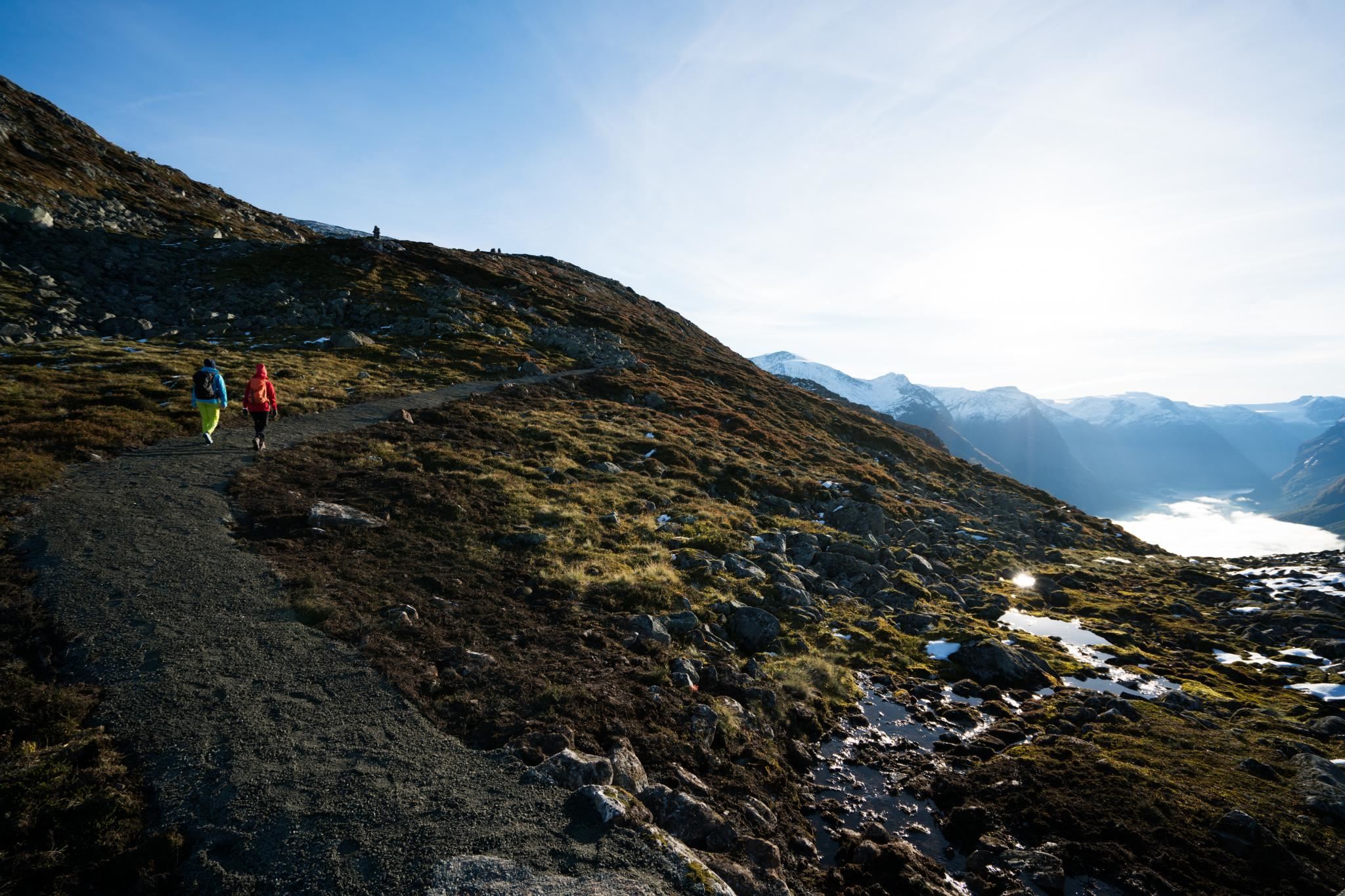 Hiker walking across the mountain landscape at Hoven, with the fjord and mountains stretching into the distance.