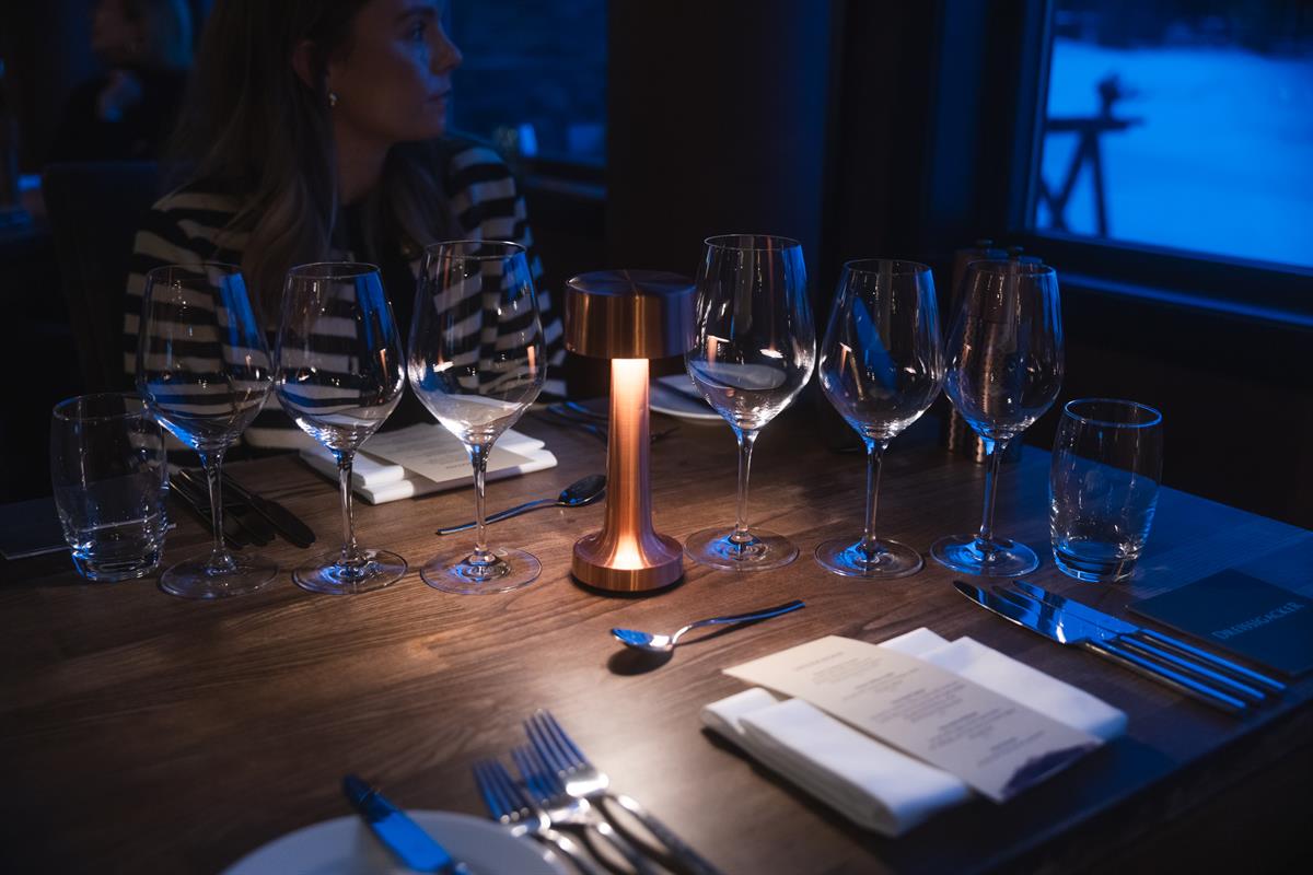 Dekketøy og levende lys på restaurantbord.