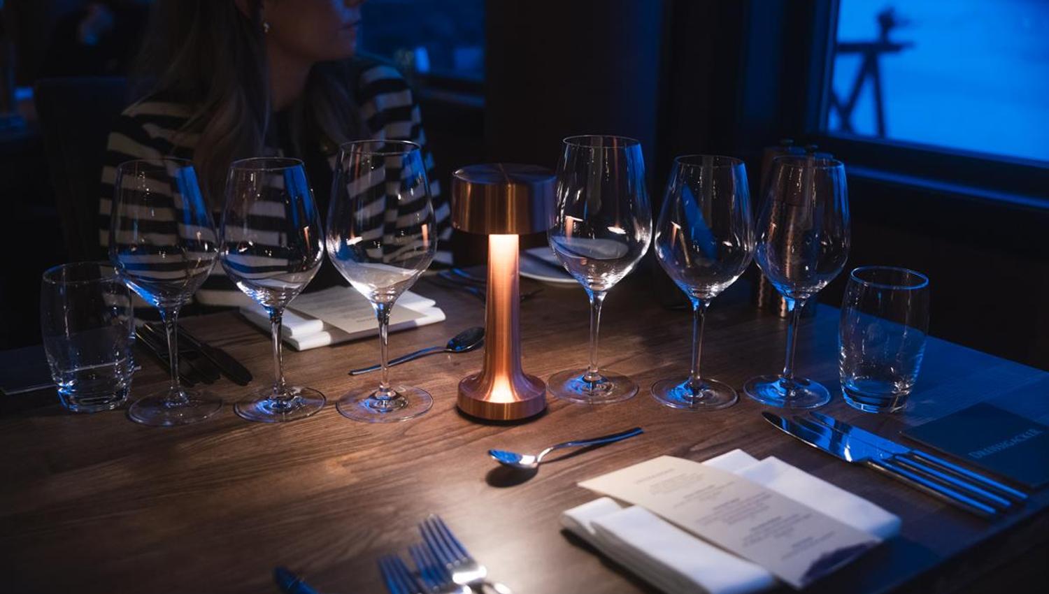 Dekketøy og levende lys på restaurantbord.