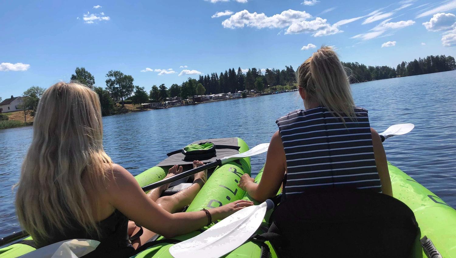 To jenter i to kajakker på vannet