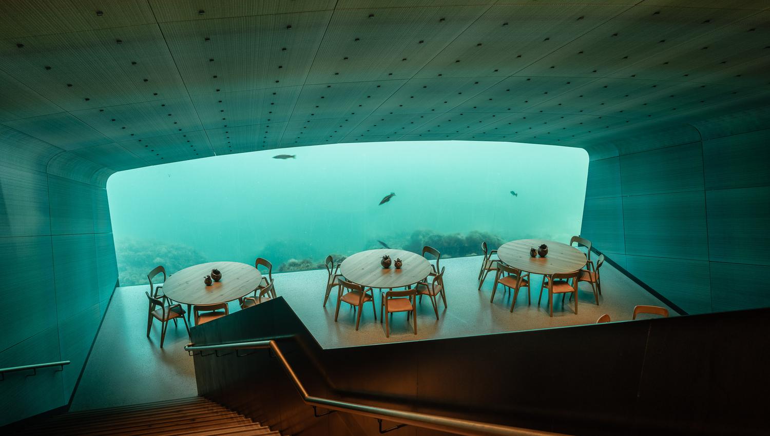 Tische und Stühle mit Blick unter das Meer, im Restaurant Under.