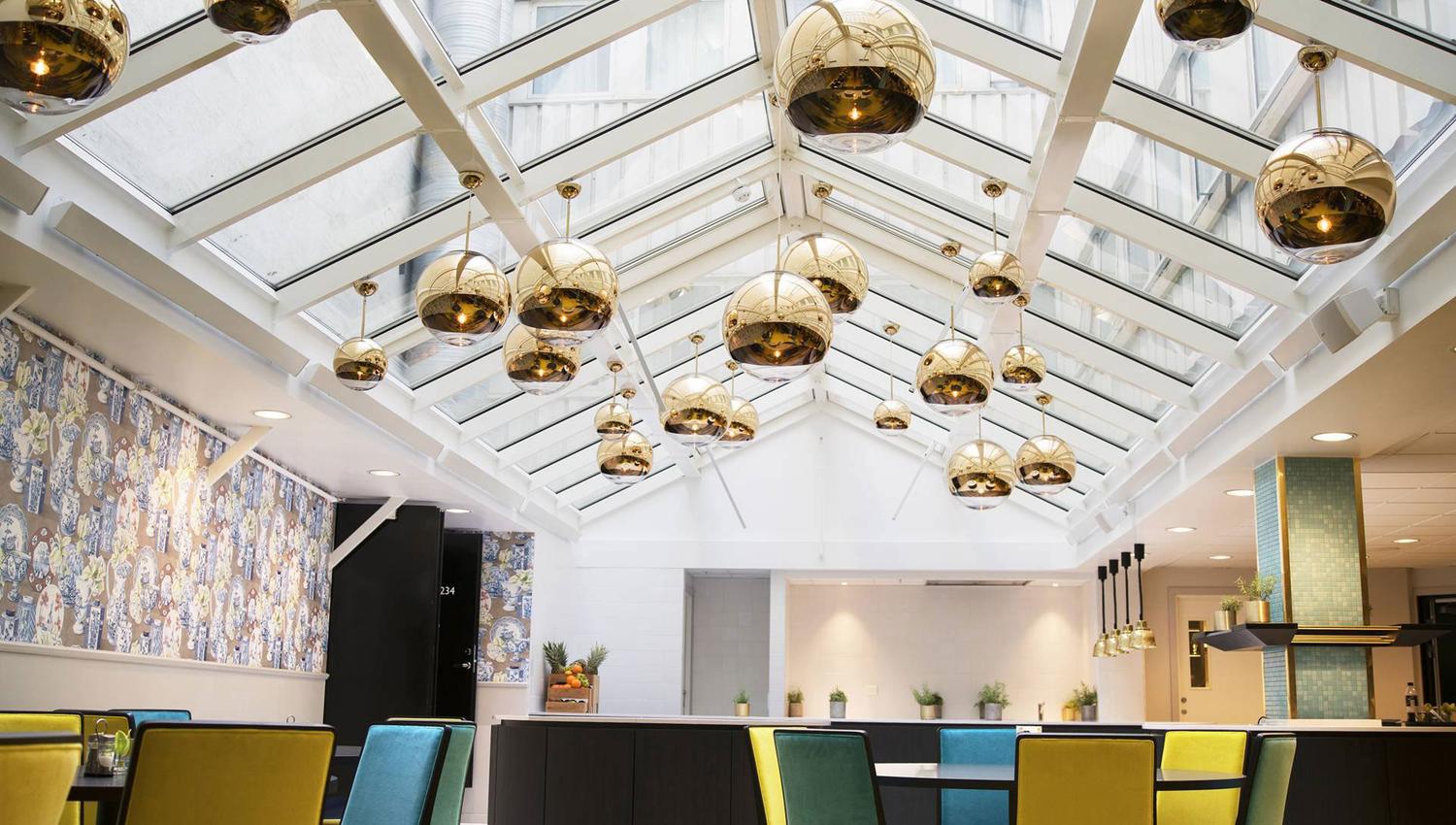 Lobby på Thon Hotel Terminus. Sittegrupper i blått og gult. Gylne taklamper. Foto