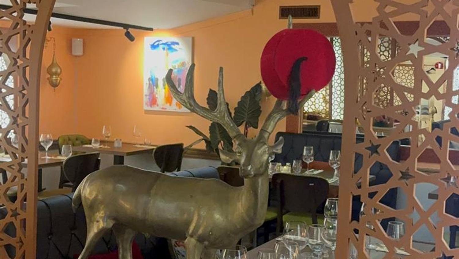 Utskårne trepaneler og en gullfarget hjort står midt i restaurantlokalet.