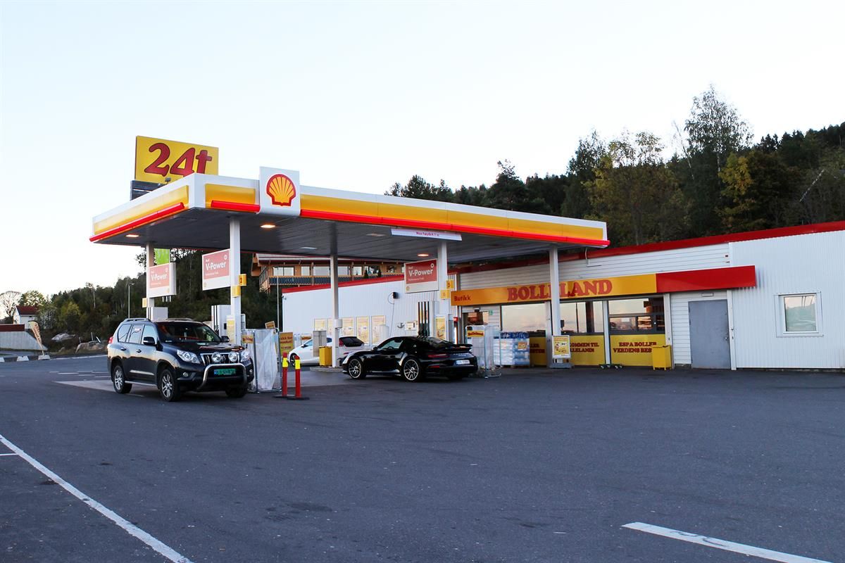 A gas station with multiple fuel pumps and a service building, viewed from the parking area on a clear day.