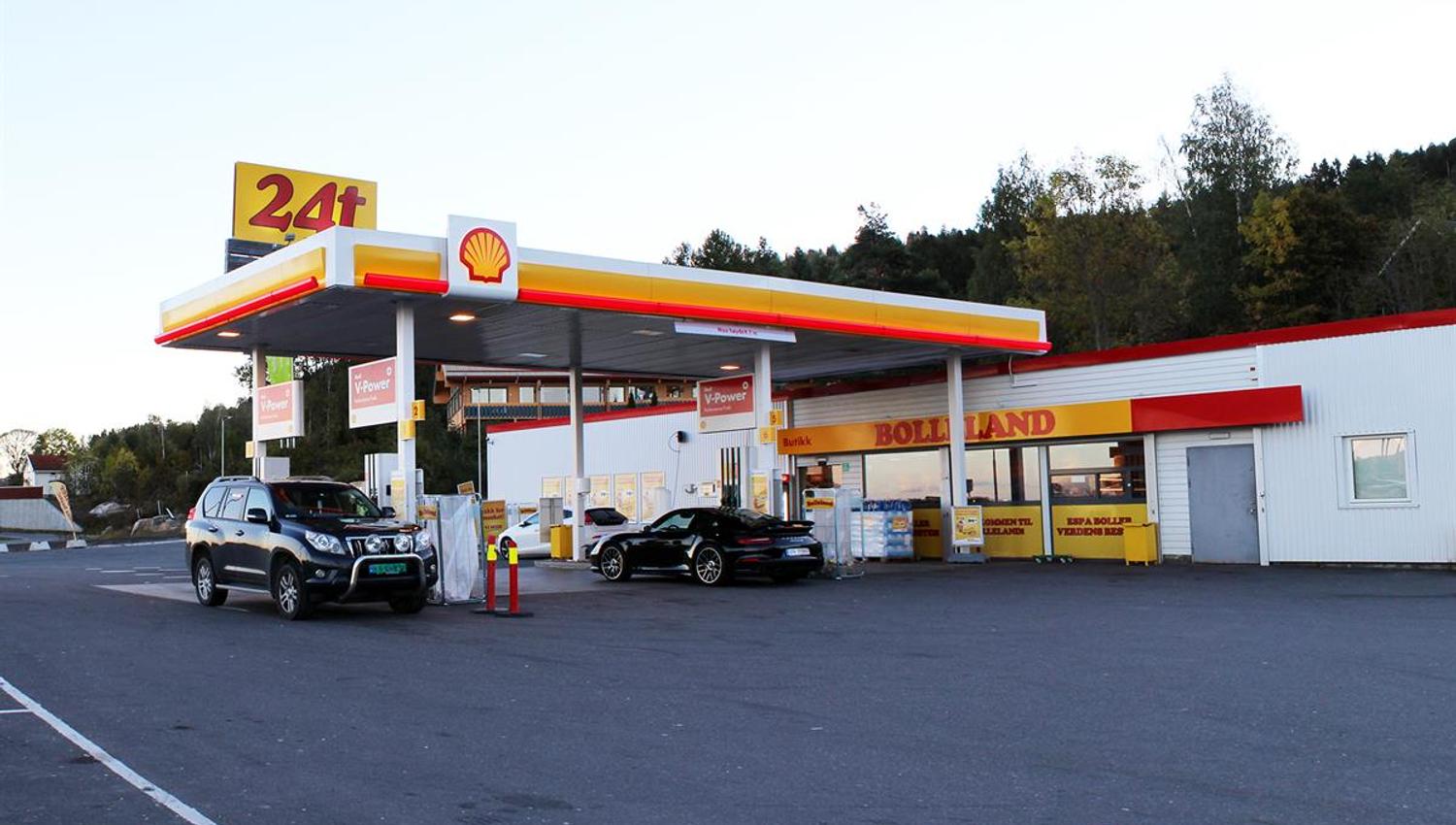 A gas station with multiple fuel pumps and a service building, viewed from the parking area on a clear day.