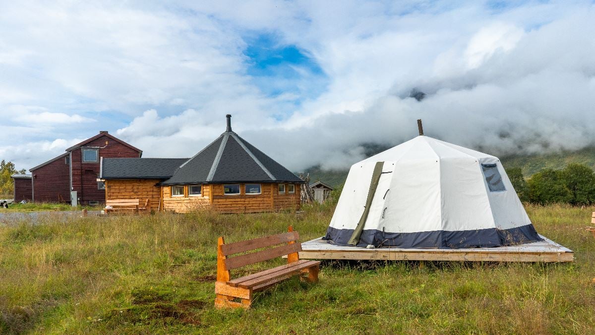 Lavvu and buildings at Tromsø Lapland’s Sámi reindeer camp, surrounded by Northern Norwegian nature.