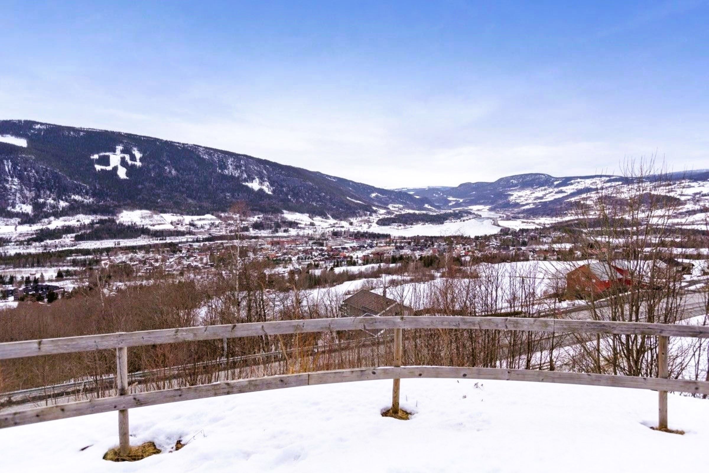 A snow-covered landscape with a fence and mountains in the background.