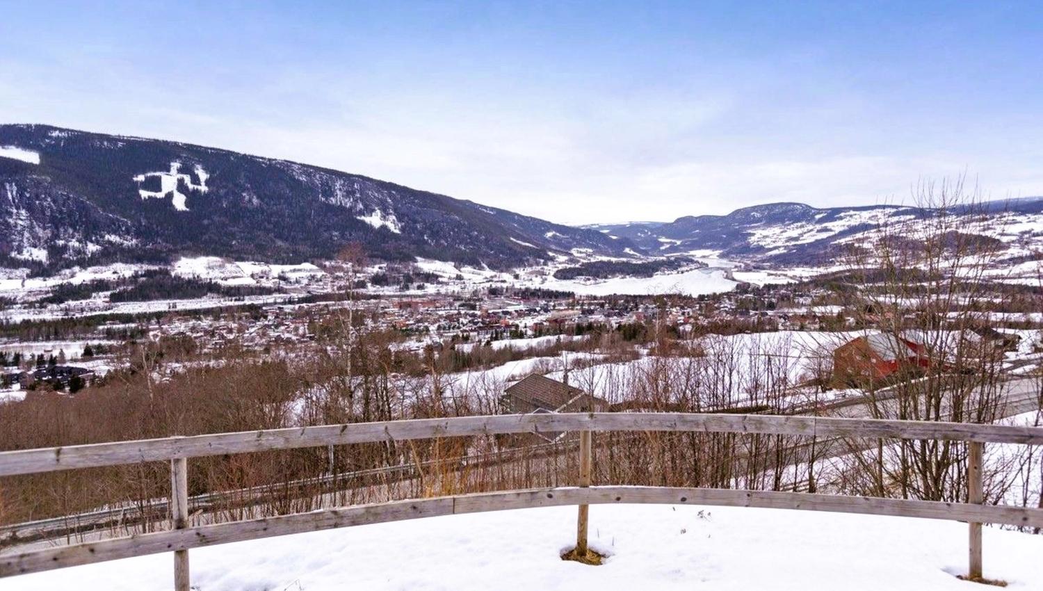A snow-covered landscape with a fence and mountains in the background.
