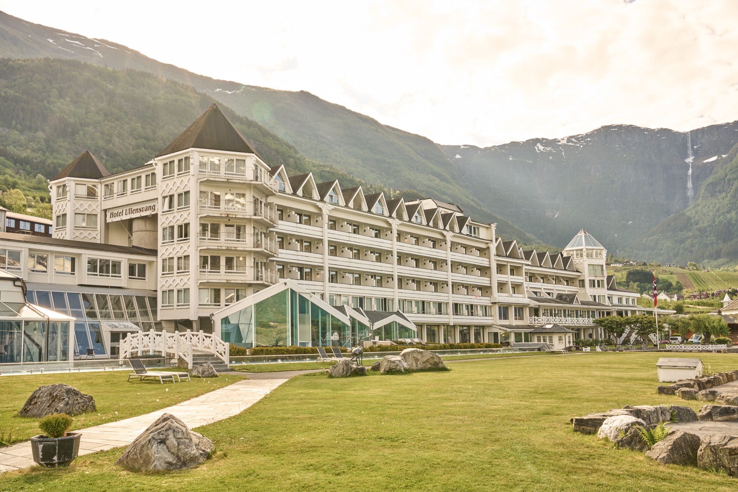 Hotel Ullensvang nestled by the Hardangerfjord, surrounded by lush gardens and dramatic mountainscapes.