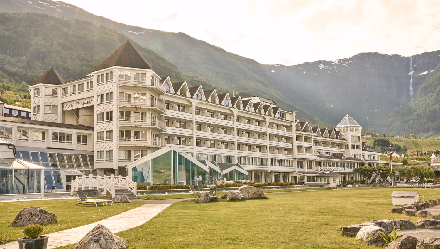 Hotel Ullensvang nestled by the Hardangerfjord, surrounded by lush gardens and dramatic mountainscapes.