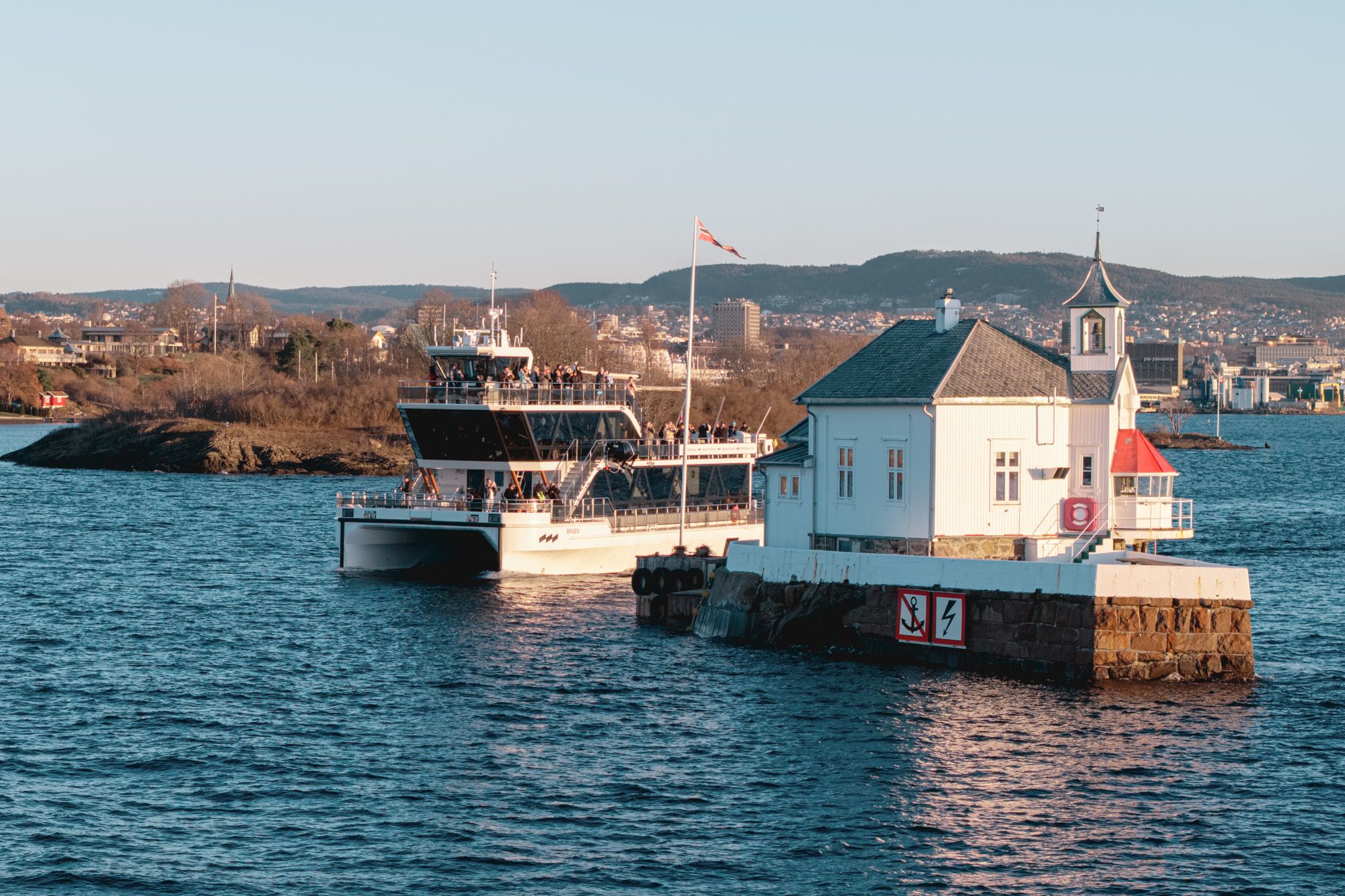 Båten som kjører forbi mellom et fyrtårn og en øy i Oslofjorden