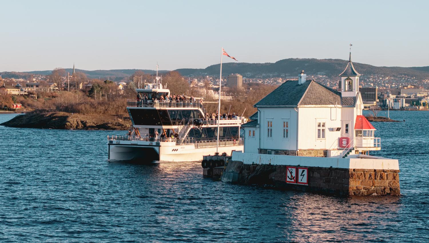 Båten som kjører forbi mellom et fyrtårn og en øy i Oslofjorden