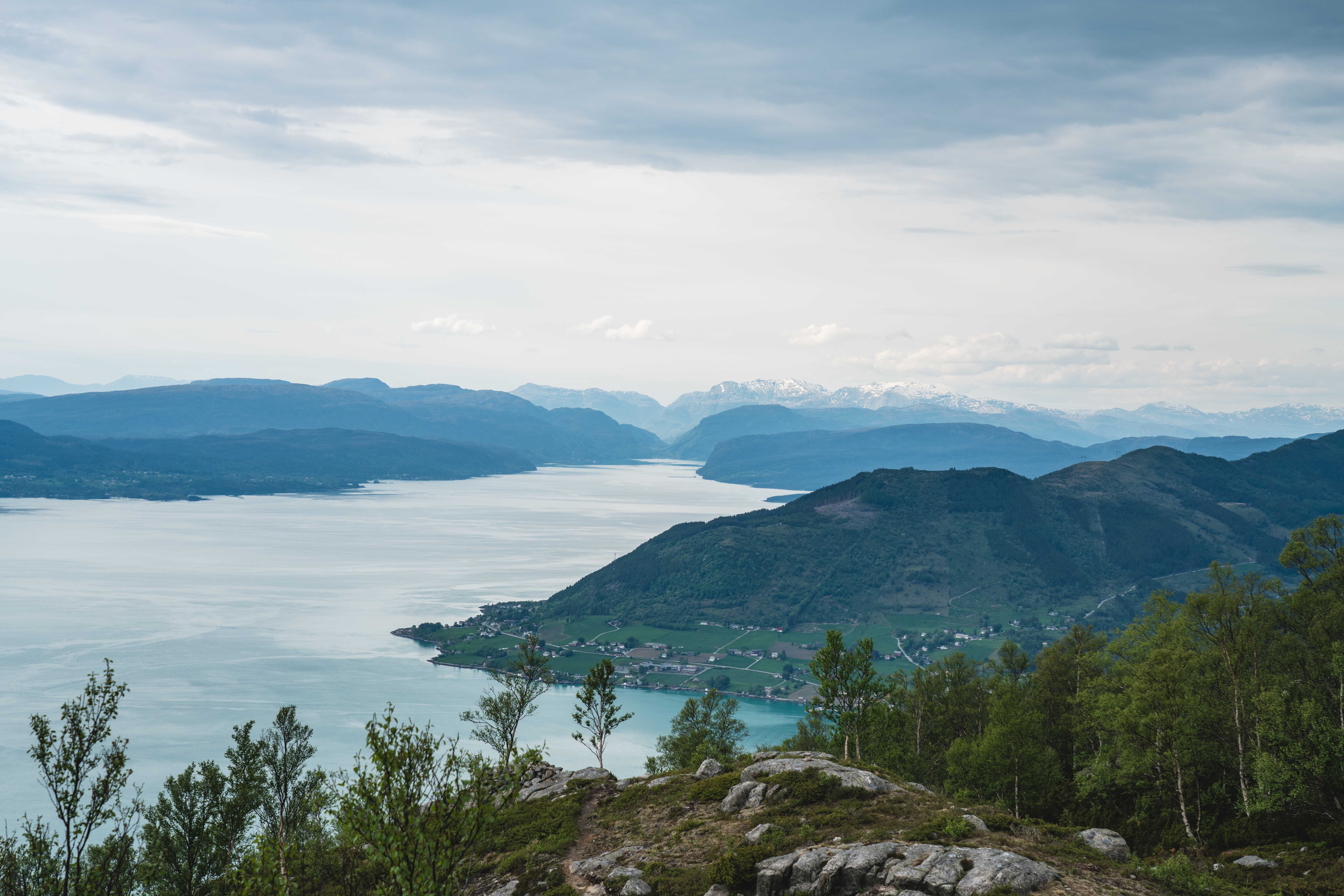 Expansive view from Kviteggjo across Hardangerfjorden toward mountain ranges with snow-covered peaks – a highlight of the trail for hikers seeking dra