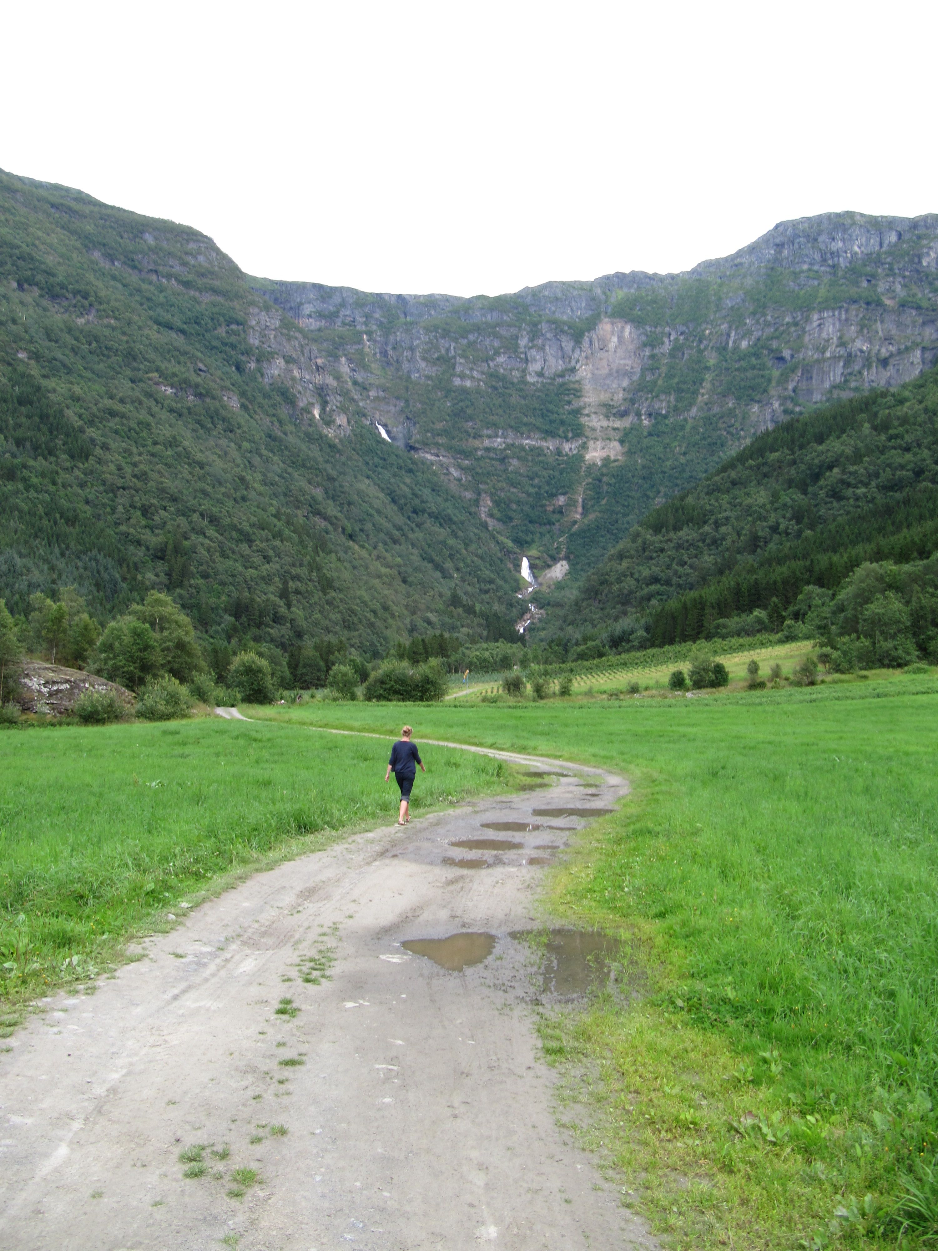 Gravel road through Elvedalen in Lofthus, Hardanger, leading towards the waterfall and steep mountains.