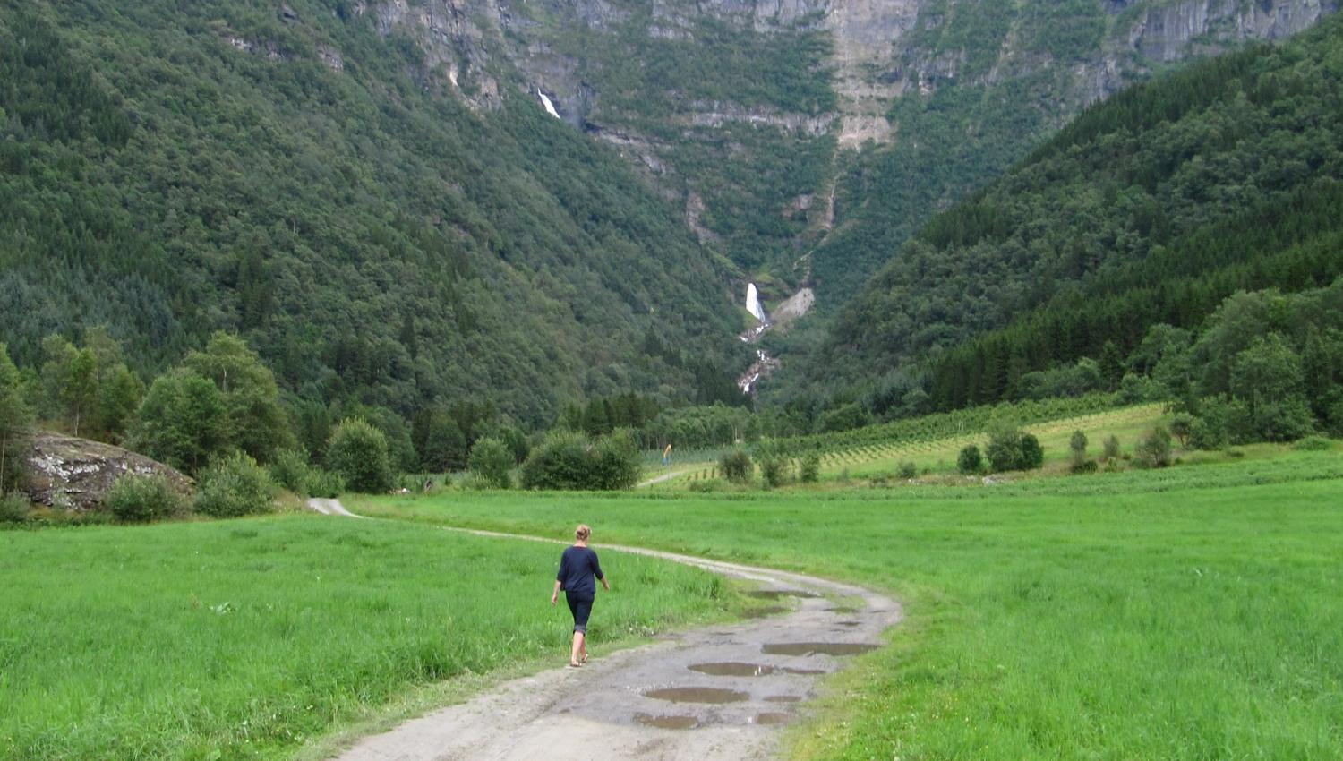 Gravel road through Elvedalen in Lofthus, Hardanger, leading towards the waterfall and steep mountains.