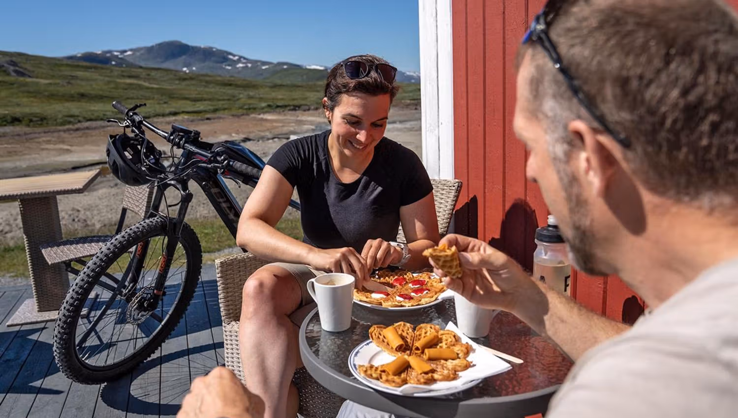 Syklister tar en pust i bakken og koser seg i solterrassen med vaffel og kaffe