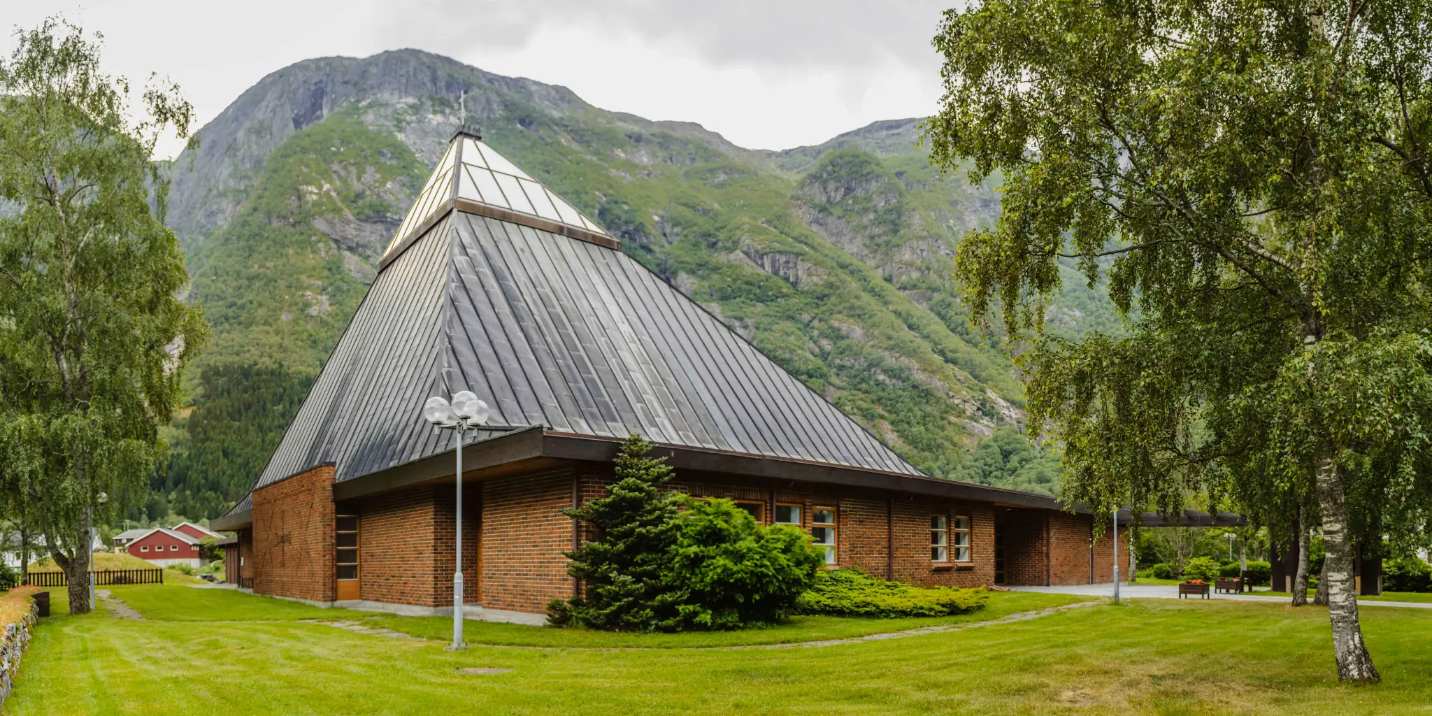 The Eidfjord new church seen from the outiside. It's made of red brick with a triangular glass ceiling top.