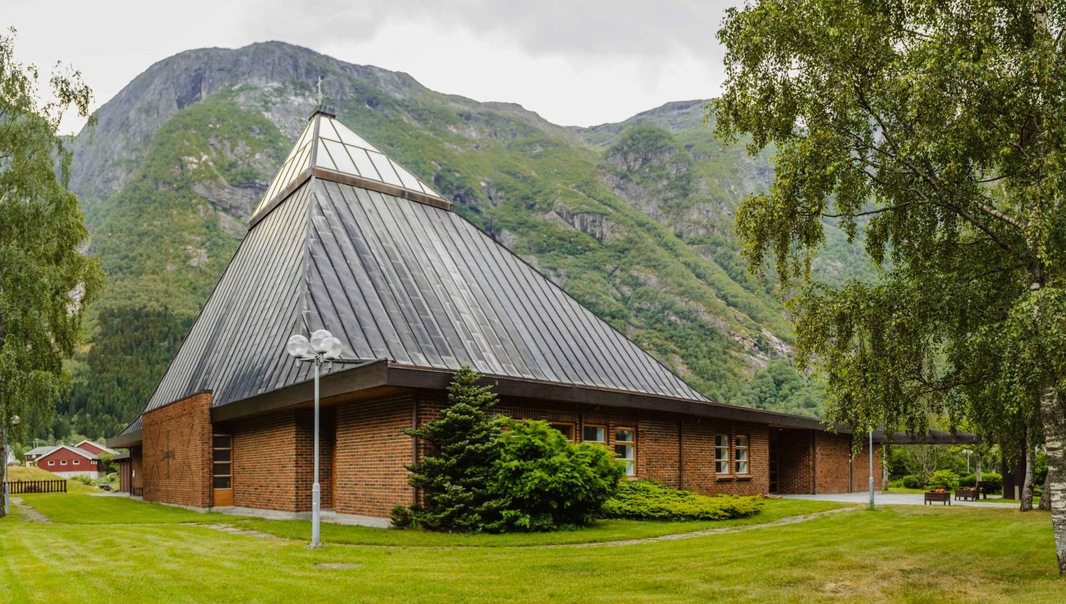 The Eidfjord new church seen from the outiside. It's made of red brick with a triangular glass ceiling top.