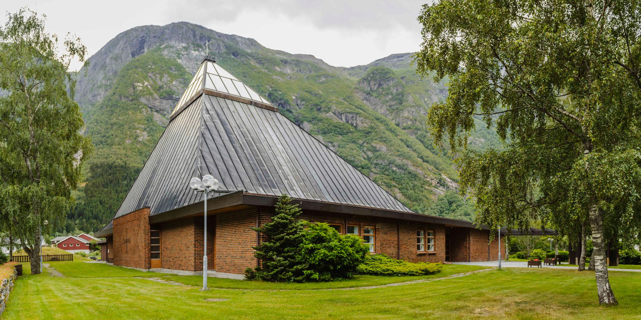The Eidfjord new church seen from the outiside. It's made of red brick with a triangular glass ceiling top.