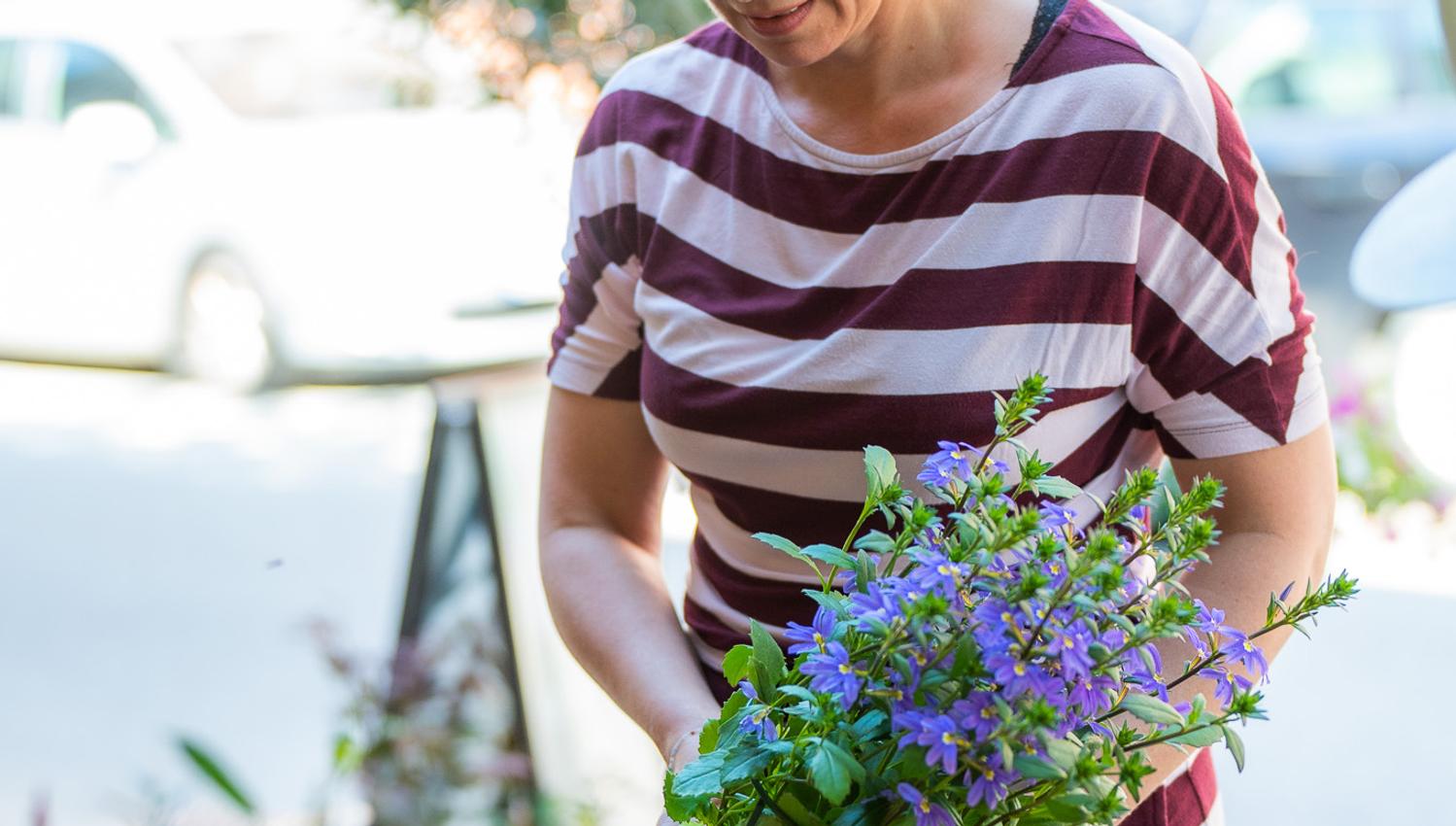 A lady shopping for flowers and considering what to choose