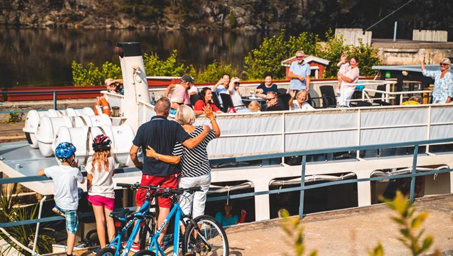 Family waving at passengers on the boat