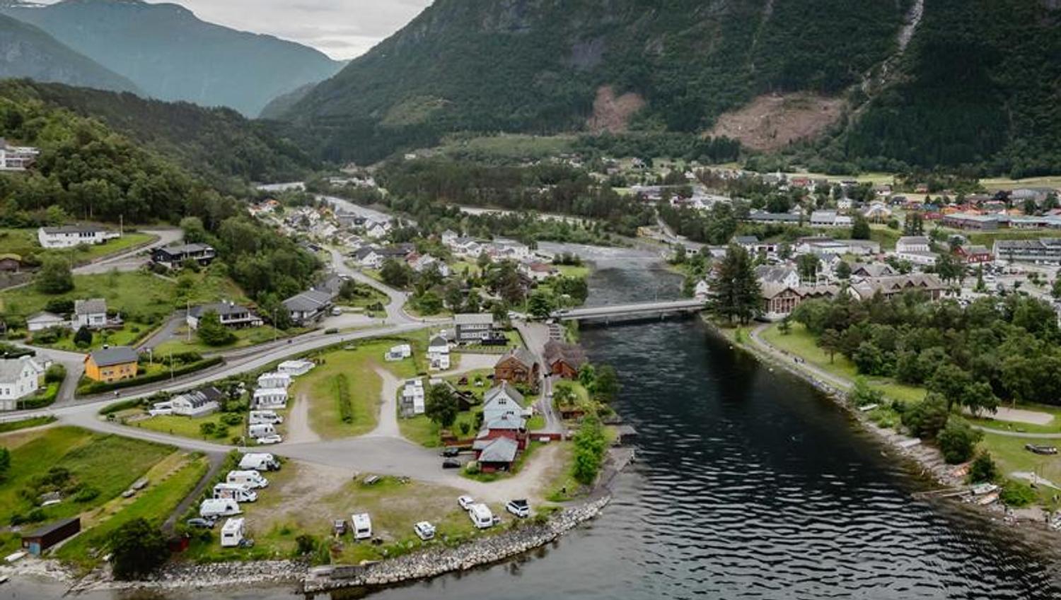 A drone photo of the camping place with the village and mountains in the background.