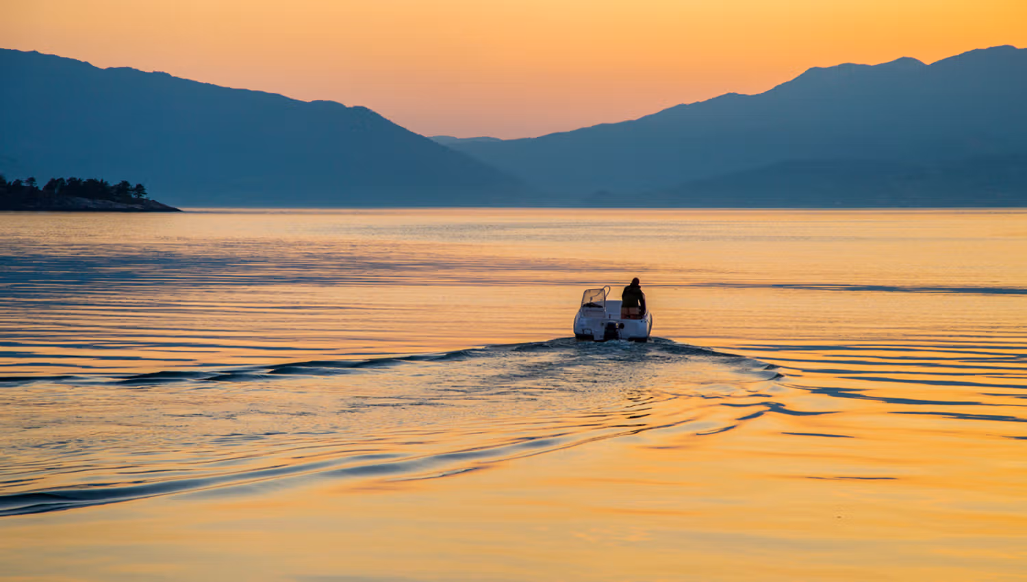 A small boat on the Hardangerfjord at sunset, with warm colors and peaceful atmosphere.