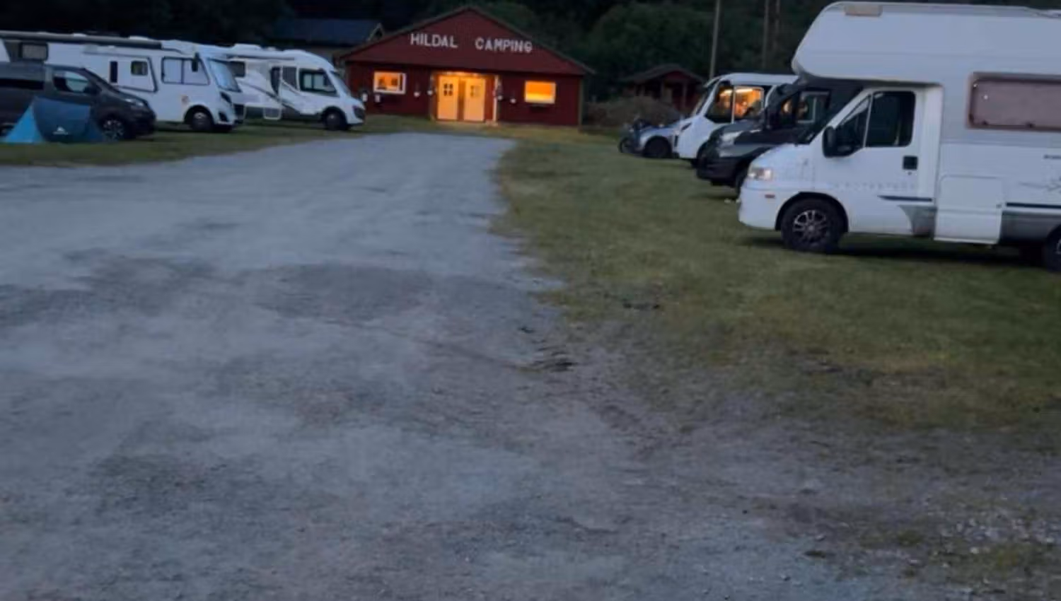 Abendstimmung auf dem Hildal Camping mit Licht aus dem Servicegebäude und geparkten Wohnmobilen.
