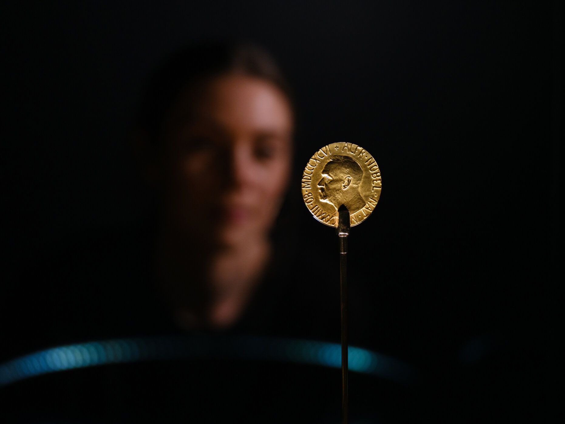Detail photo of gold medal with a face in the background.
