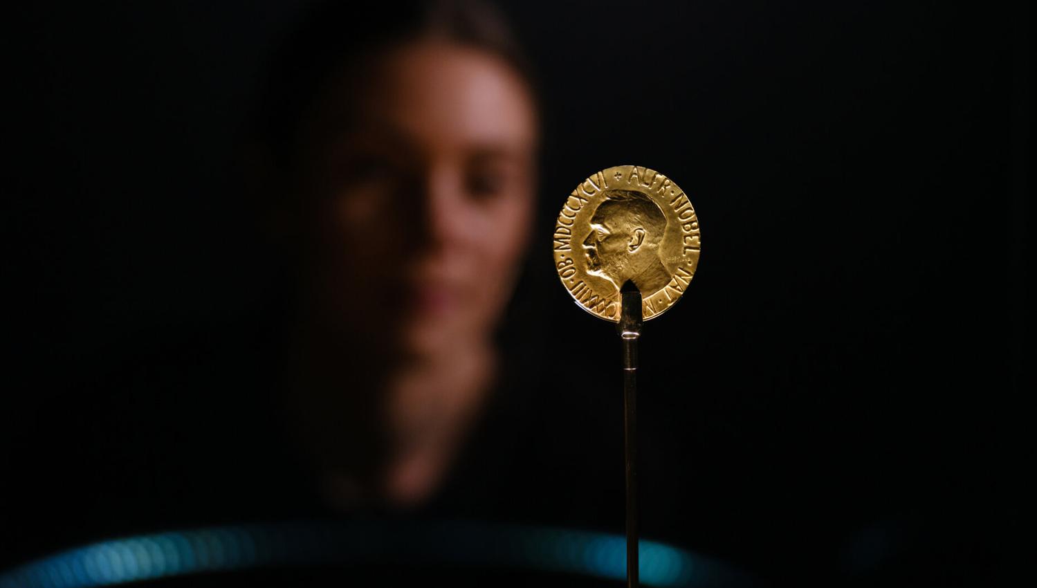 Detail photo of gold medal with a face in the background.