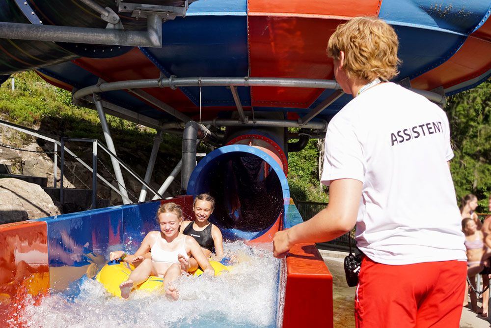 employee from Bø Sommaland assists children at the bottom of a slide