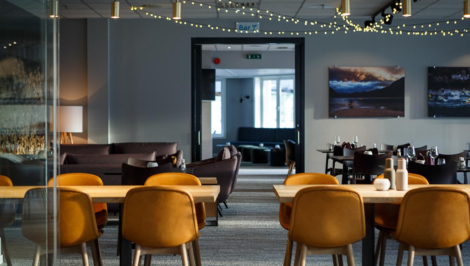 The diningroom at the restaurant with tables, chairs and light chains hanging in the ceiling.