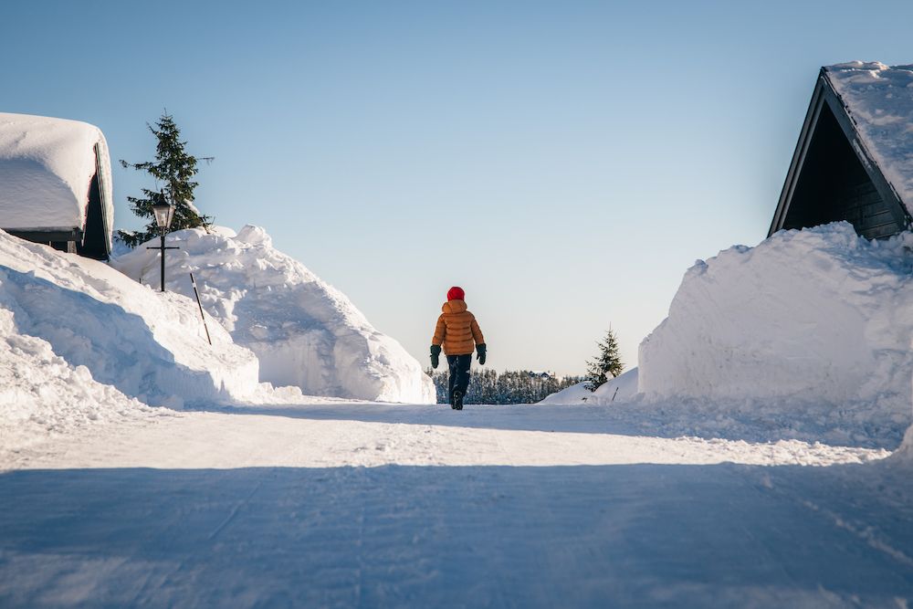 person walks on a snow-covered road between the cabins at Lifjell Tunet in Bø 