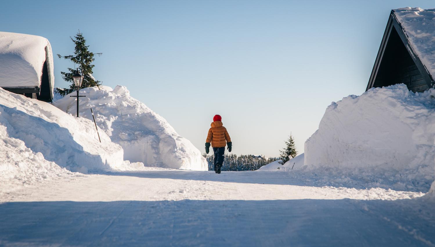 person walks on a snow-covered road between the cabins at Lifjell Tunet in Bø