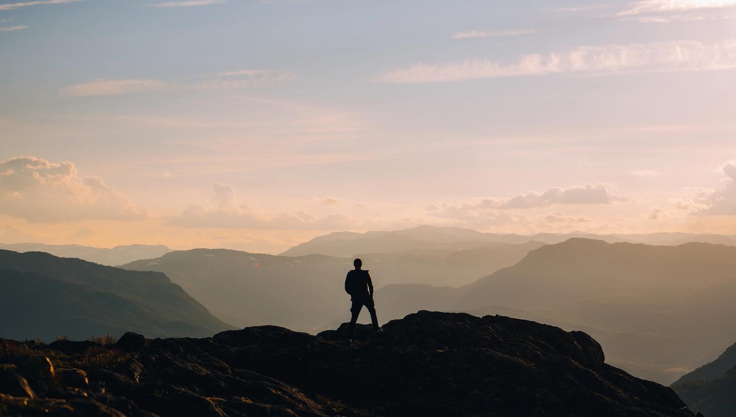 Person på toppen av et fjell i morgen disen