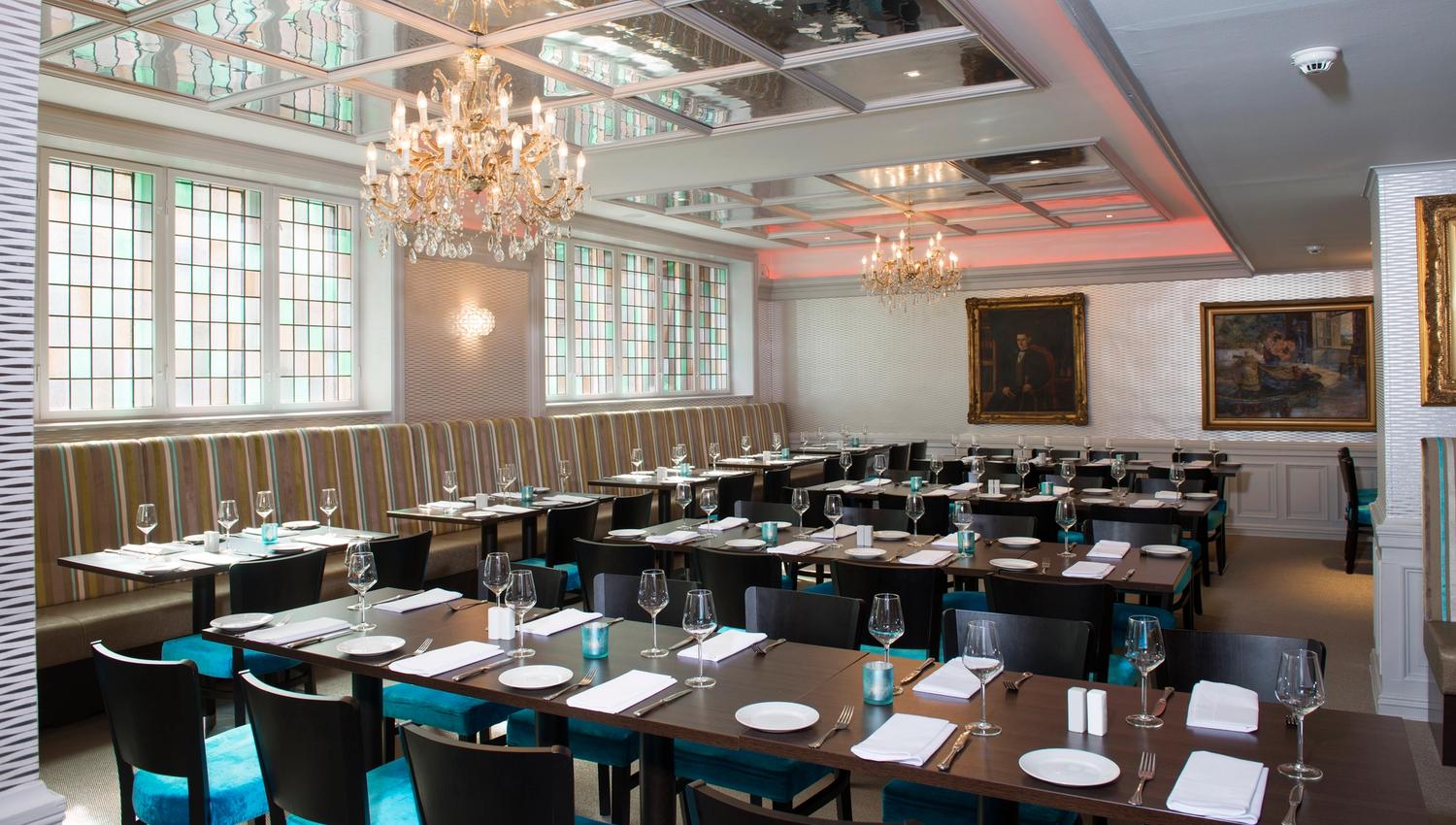 Dining room with turquoise chairs, wooden tables and large windows. Thon Hotel Slottsparken, Oslo. Photo