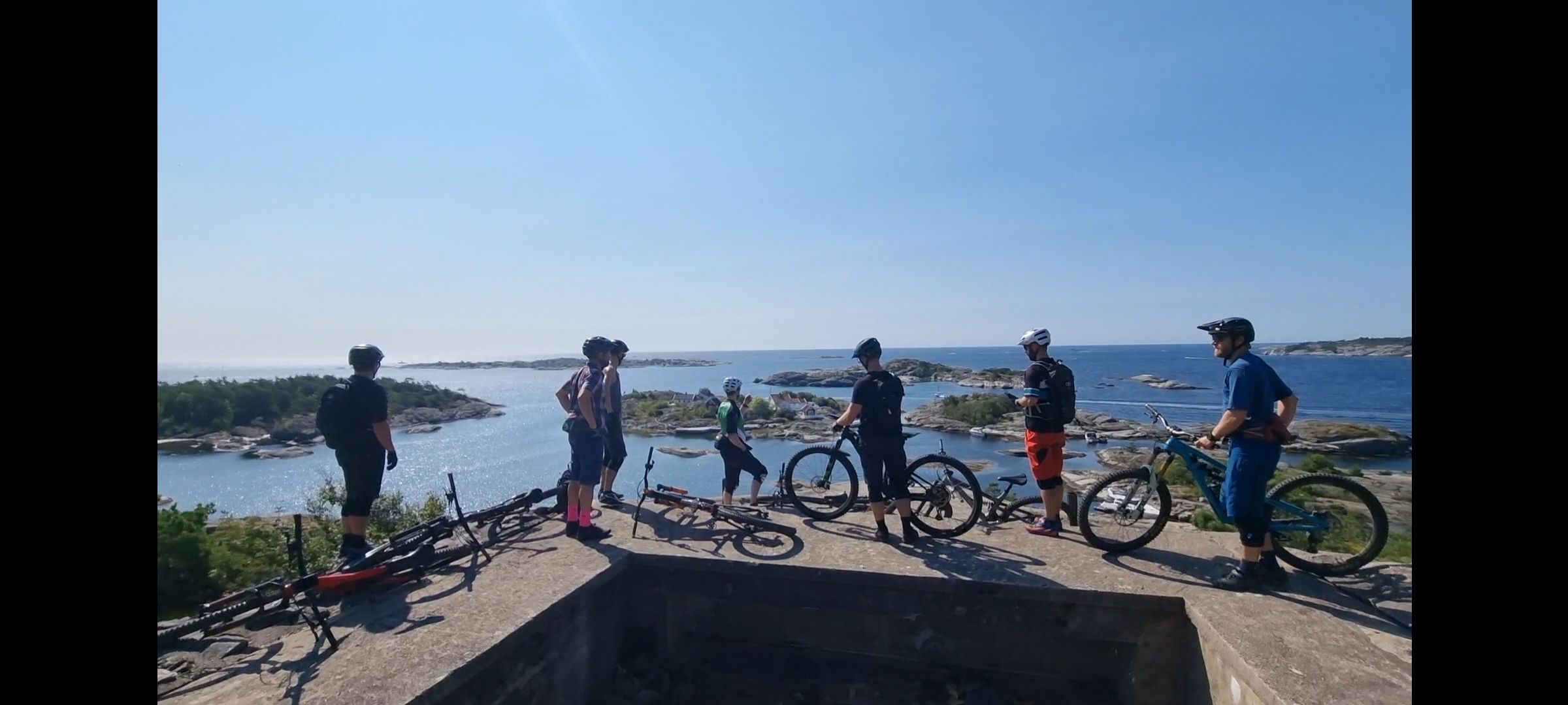 group of cyclists stands and looks out over the Kragerø archipelago