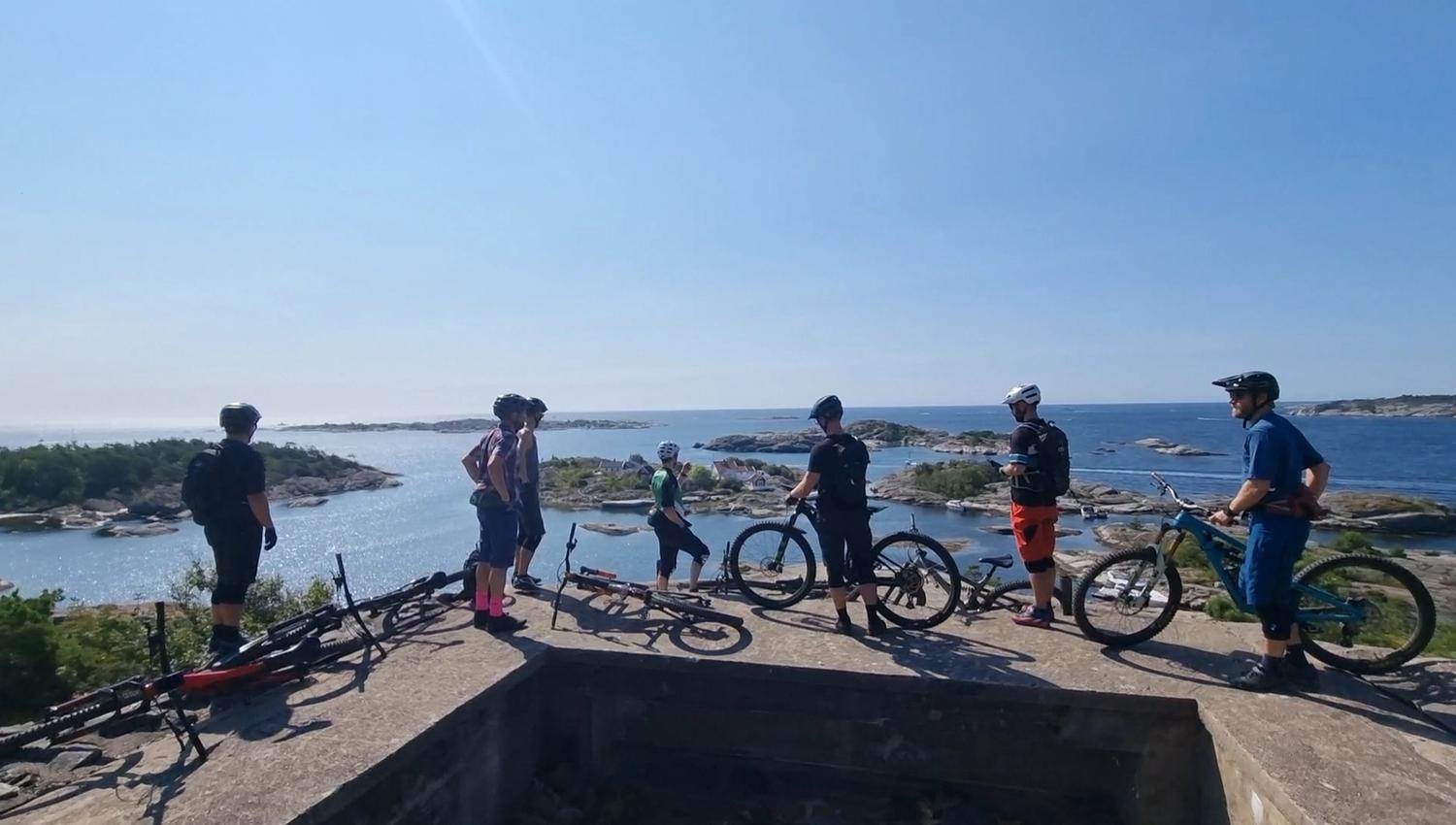 group of cyclists stands and looks out over the Kragerø archipelago