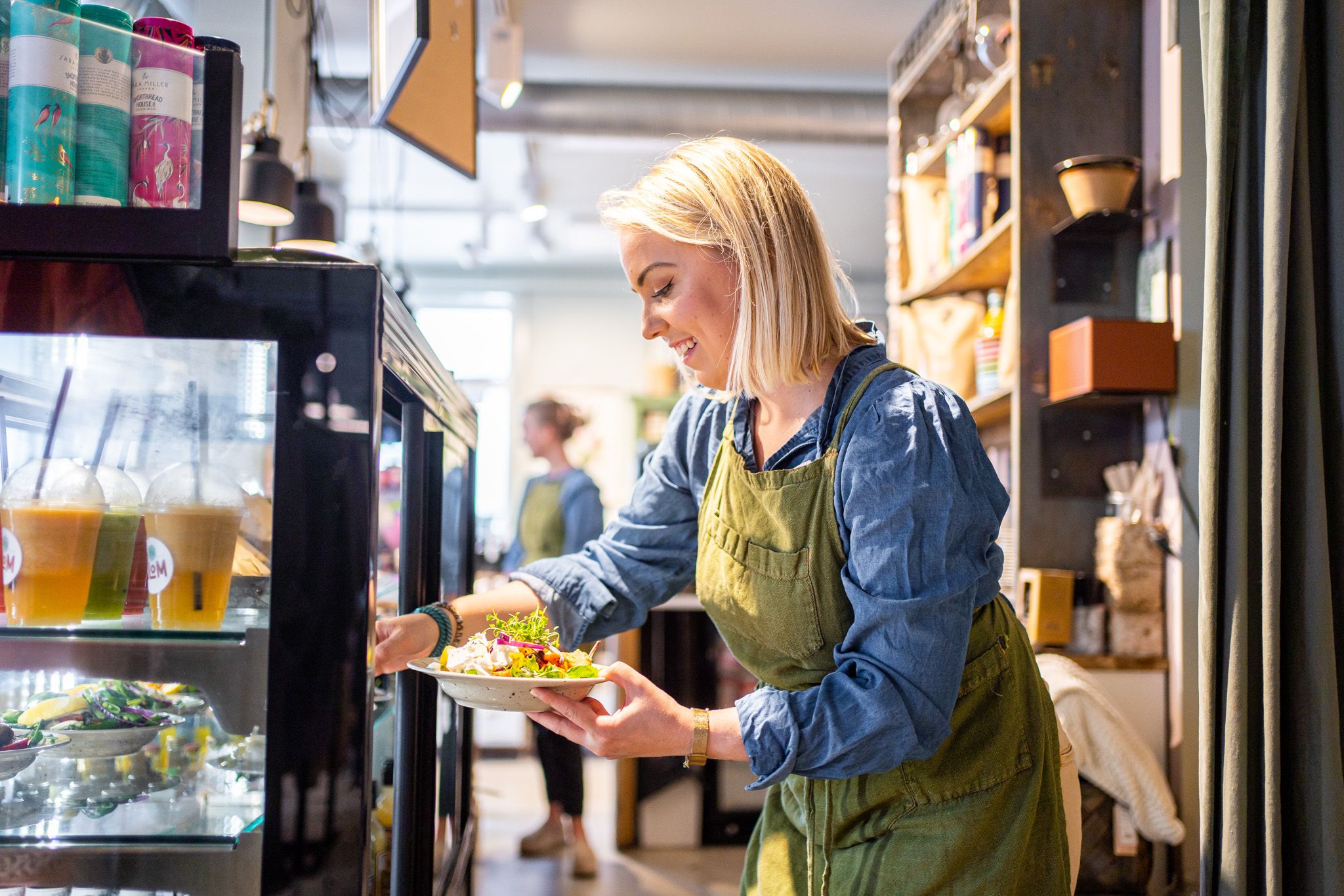 a woman getting a salad out of a fridge 