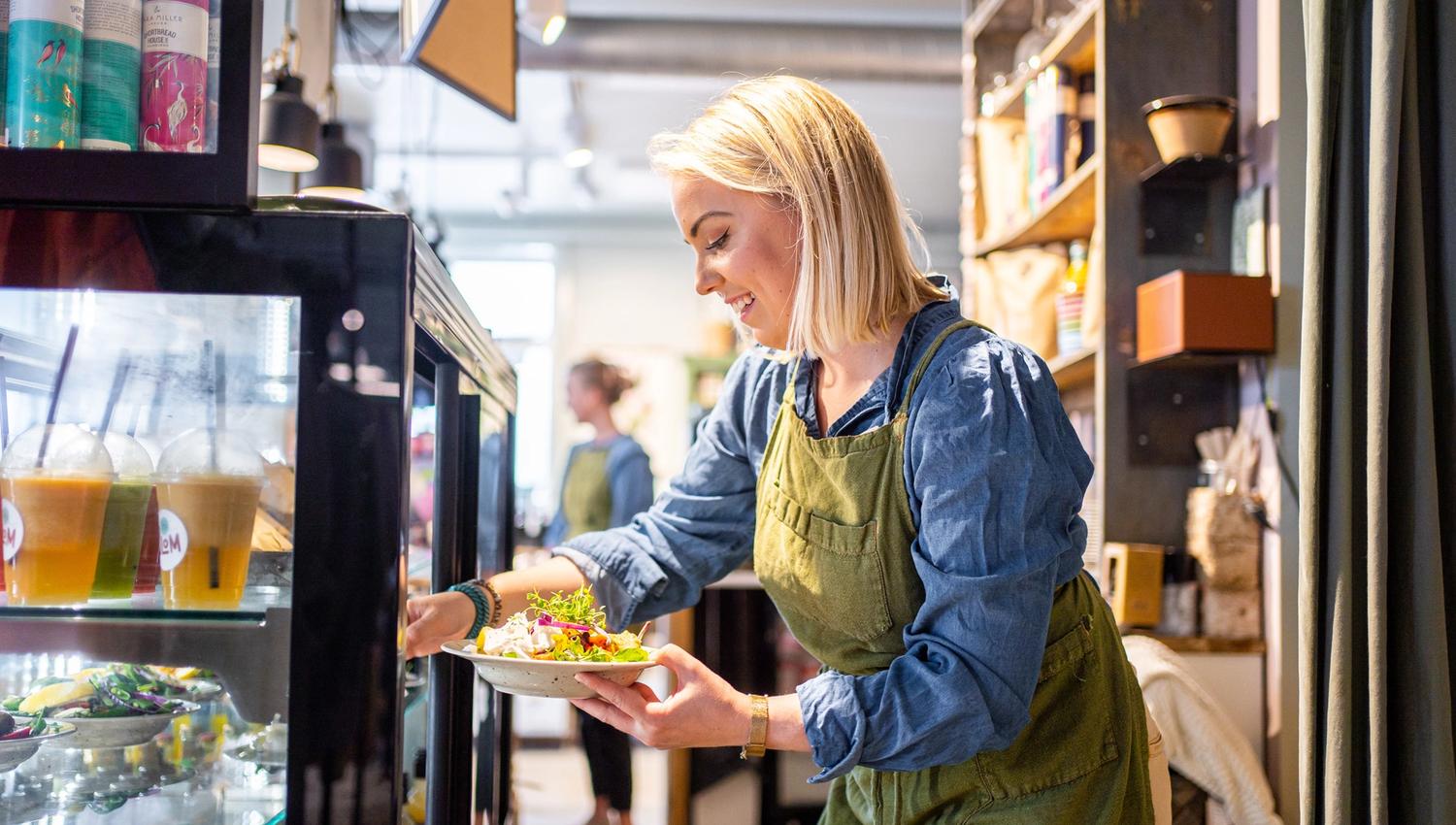a woman getting a salad out of a fridge