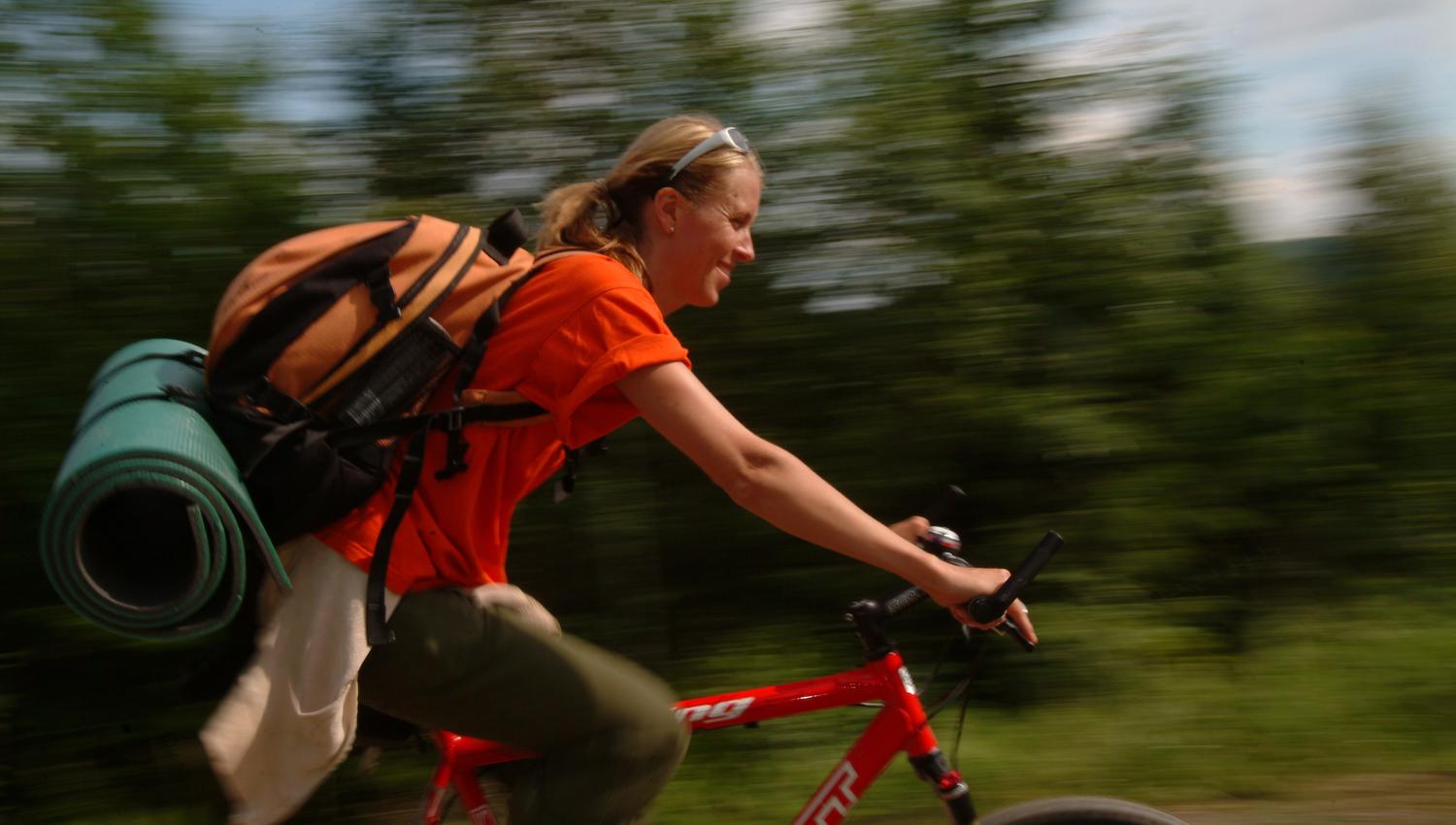 a woman with a backpack on a bicycle