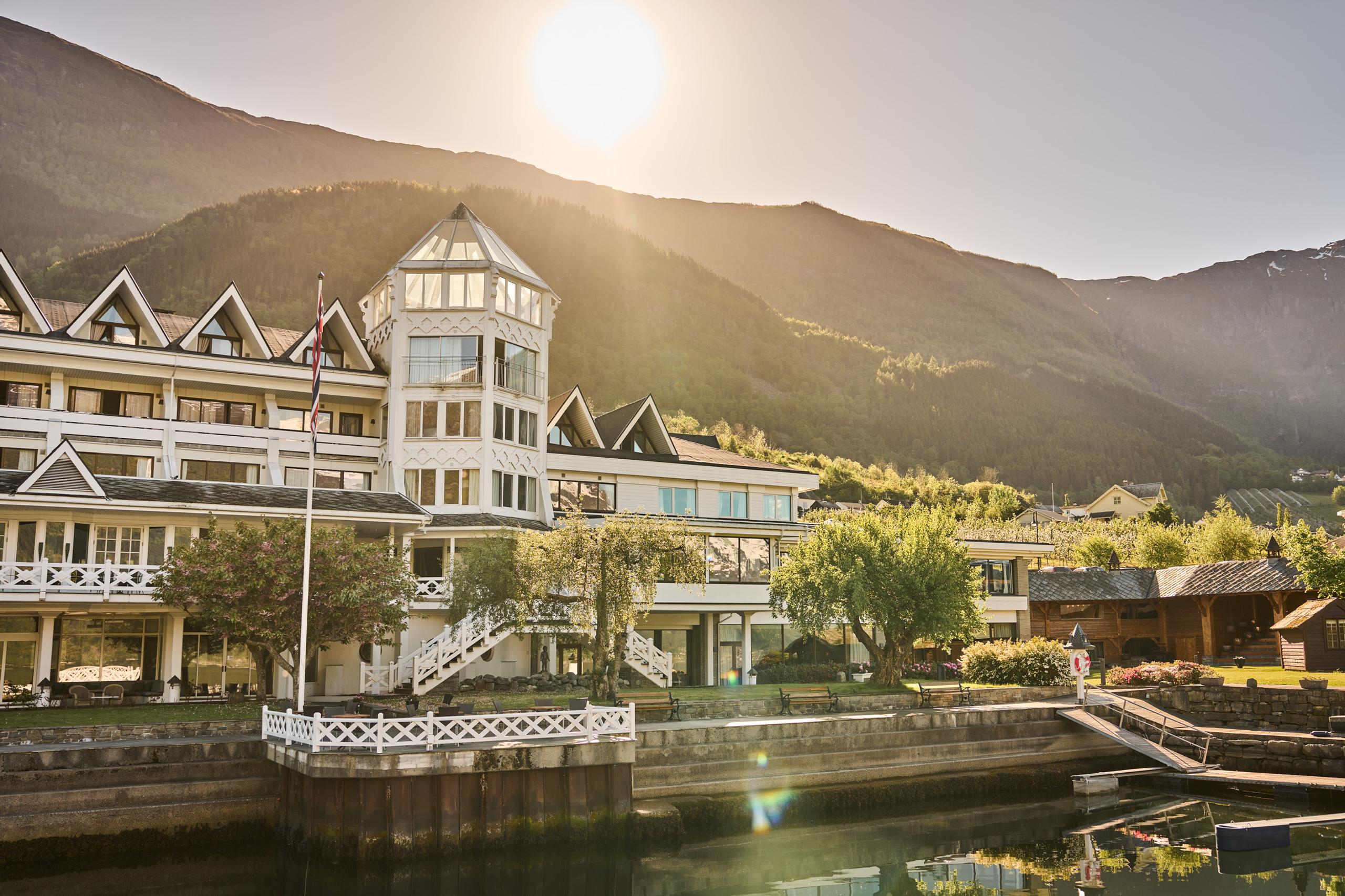 Das Hotel Ullensvang im goldenen Abendlicht – mit Garten und Blick auf den Hardangerfjord.