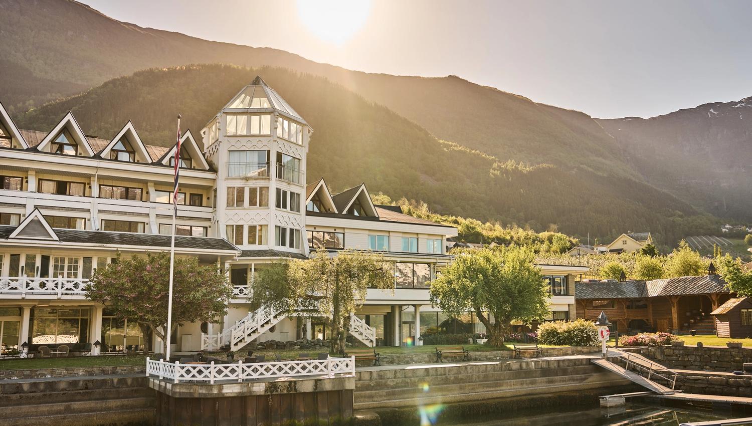 Hotel Ullensvang glowing in the golden evening light, surrounded by gardens and fjord views.